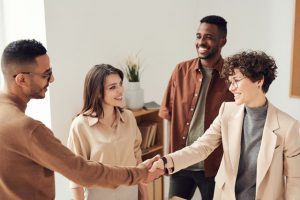 A seller, two buyers, and the investor shaking hands on a real estate deal.