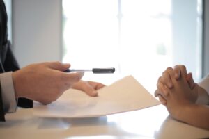 A man giving a contract to a woman for her to sign it